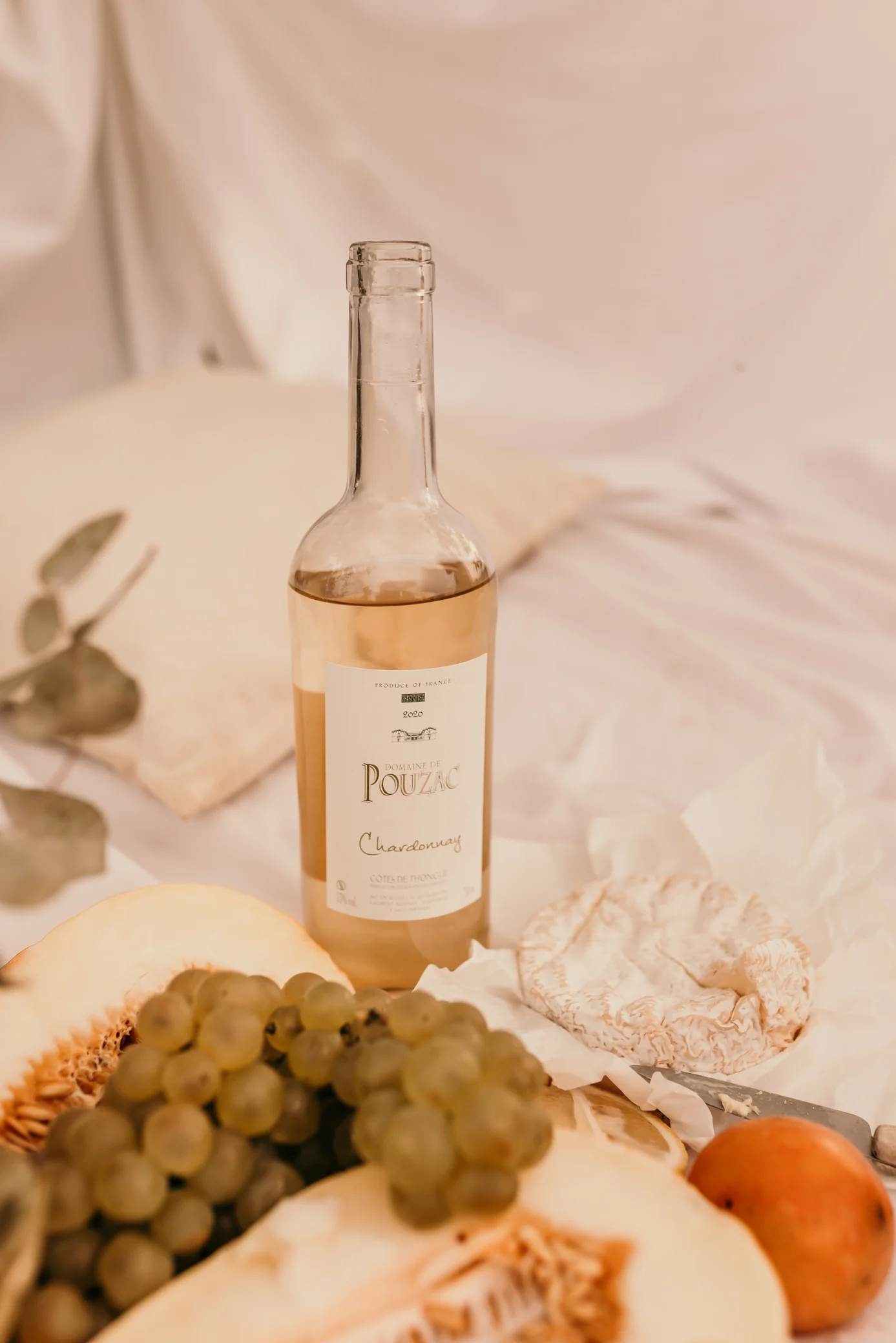 Packshot lifestyle Chardonnay 2020 avec grappe, fromage, melon. Pique-nique provencal.