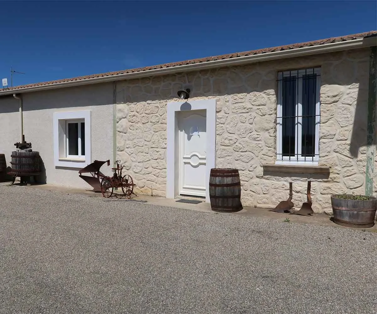 Facade du batiment d'accueil, vieux pressoir et barriques. Caractere du mas.
